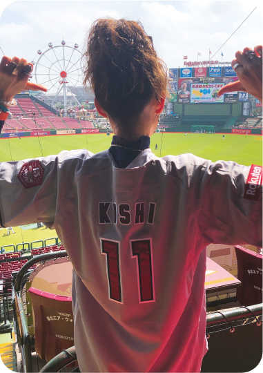 画像：スポーツ観戦をするユニフォーム姿の佐々木さんの後ろ姿